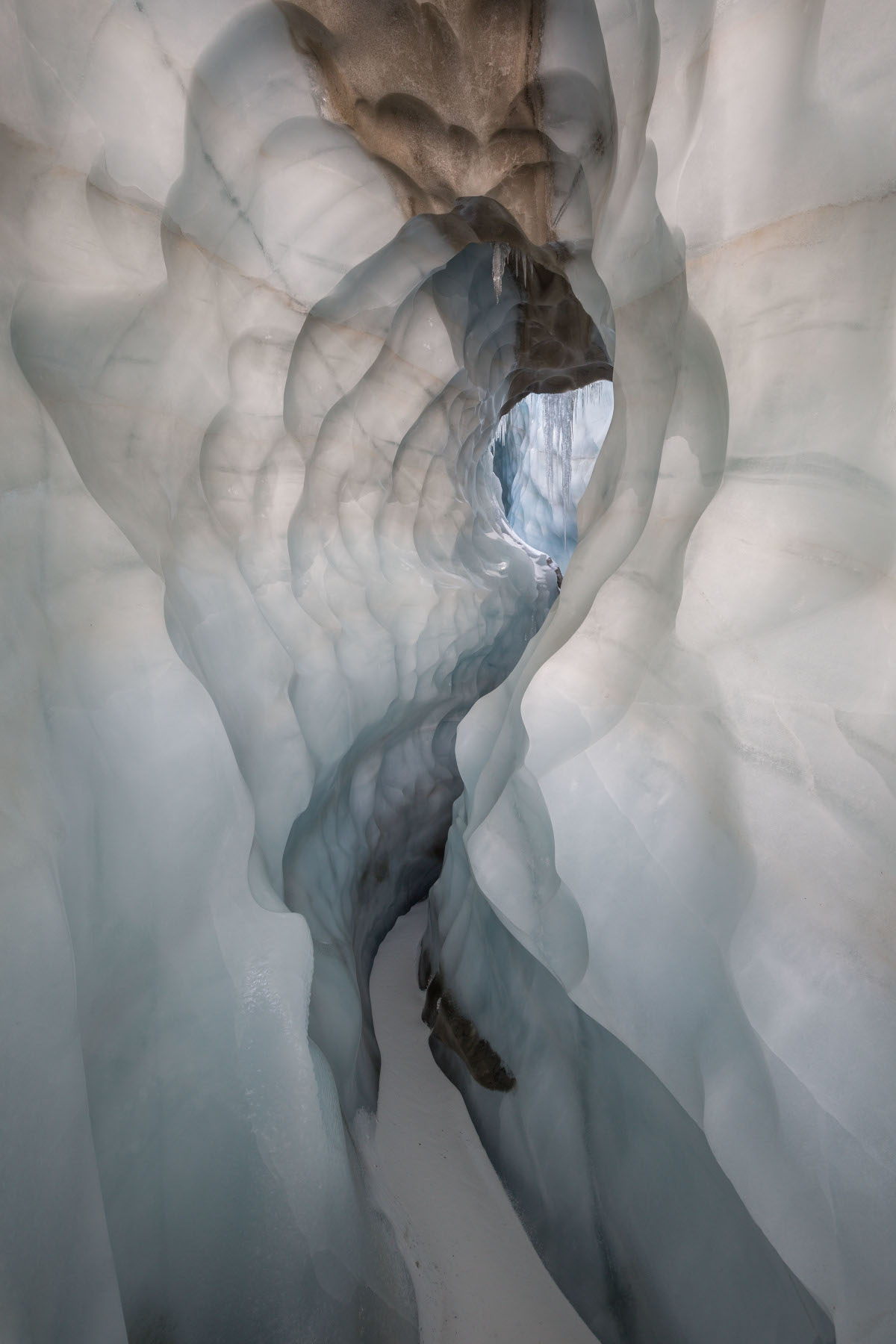 11 octobre 2021. Moulin latéral de la grande doline, glacier de la Plaine Morte. Très grande galerie en forme de trou de serrure, avec névé brun au plafond et arrivée d'un moulin dont on voit la clarté au loin.
